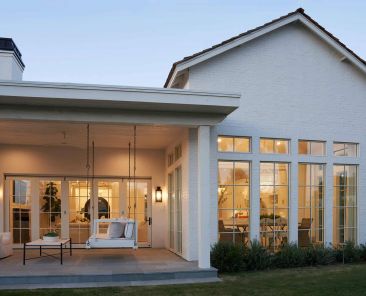 Evening exterior living space of a luxury residence designed by Custom Homes Arizona builders, featuring covered patios and expansive glass doors.