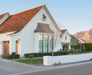 Side elevation of a custom home in Arcadia by home builder az, featuring a three-car garage with Camelback Mountain in the background.