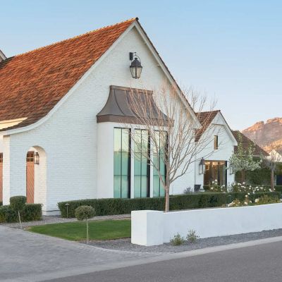 Side elevation of a custom home in Arcadia by home builder az, featuring a three-car garage with Camelback Mountain in the background.